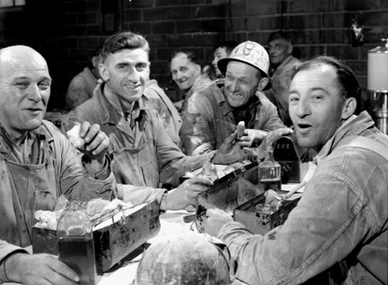 Workers of the Asbestos Corporation enjoying their lunch at lunch tables
                provided by the corporation.