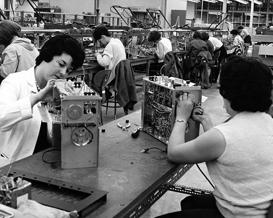 A photograph of women seated and working on component boxes for stereos at the Clairtone Sound assembly line at Pictou Estates.