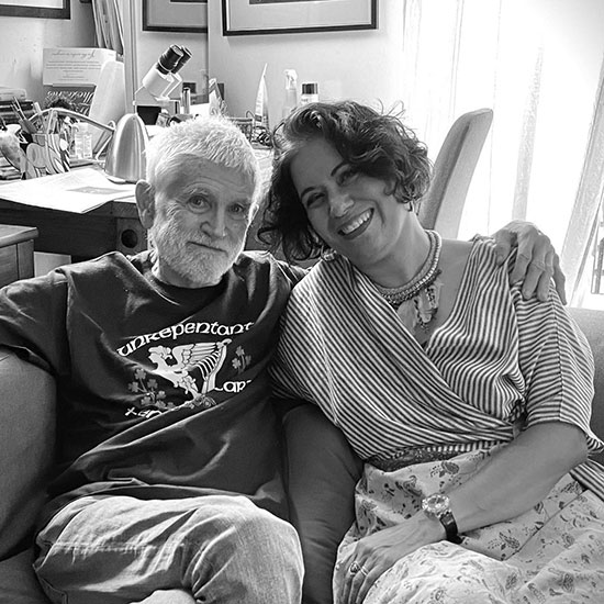 A photograph of Mike Davis sitting with his wife Alessandra.