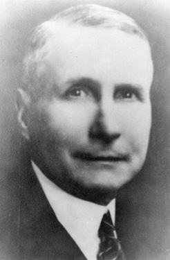 A head shot of a middle aged white male wearing a suit.